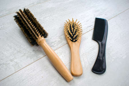 Close up of natural wooden hairbrushes. Massage, round with a bristle, plastic combs with handle isolated on a wood background.の写真素材