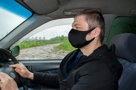 Young man in protective sterile medical mask driving car. Coronavirus covid-19, virus, pandemic....