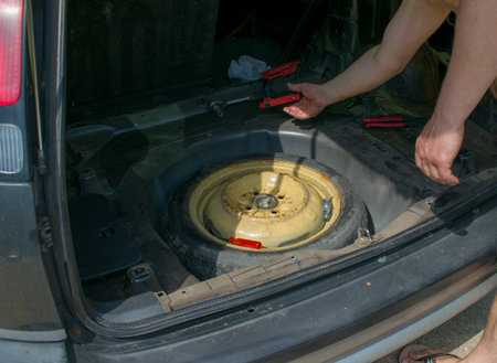 Mechanic open car hood checking car on the road after breakdown problem. Young man maintenance, fixing trouble car repair through a trunk on the road street.の写真素材