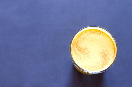 Healthy golden milk with turmeric and honey on a blue background and tiextile. Diet, vegan and detox...