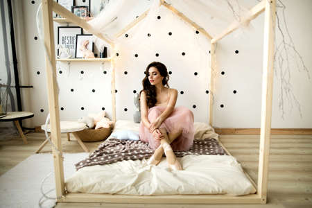 Beautiful portrait of a ballerina girl sitting on bedの写真素材
