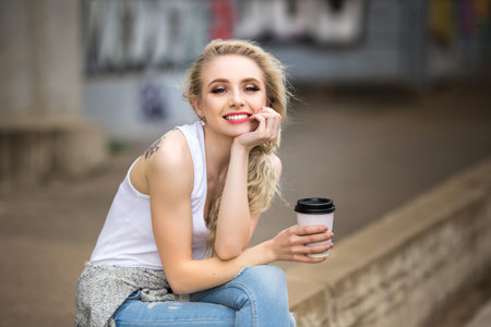 Beautiful girl drinks coffee on the streetの写真素材