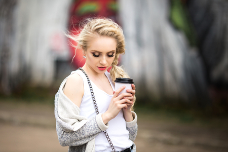 Beautiful sad girl drinking coffee on the streetの写真素材