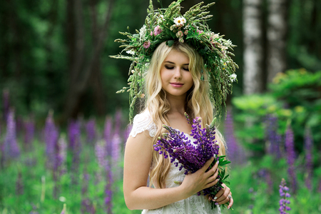 Beautiful girl in white dress in lupine fieldの写真素材