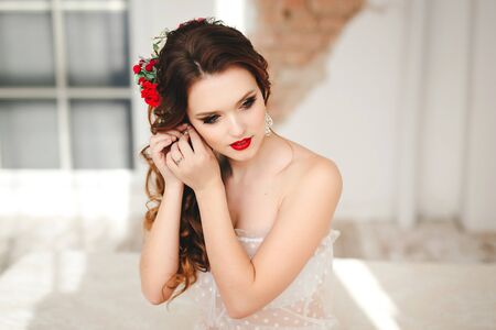 Beautiful bride with bright make-up sits on the bedの写真素材