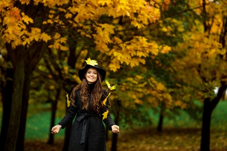 Young woman with autumn leaves in hand and fall yellow maple garden backgroundの写真素材