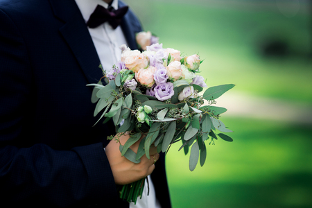 Wedding bouquet with purple flowers in the hands of the groomの写真素材