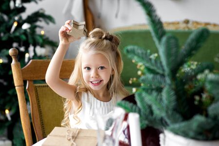 Merry Christmas and Happy Holidays. Cheerful child girl opening a Christmas present.の写真素材