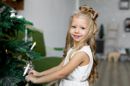 Merry Christmas and Happy Holidays. little girl decorates a Christmas tree.の写真素材
