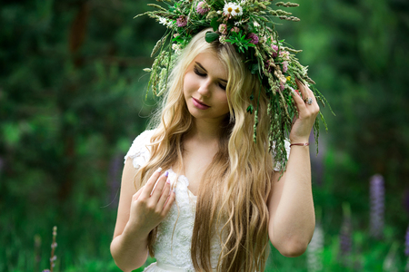 Romantic girl in a wreath of wild flowers in a field. Summer life. Beautyの写真素材
