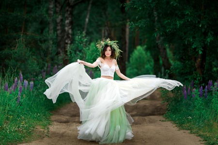 the bride in a beautiful white dress and a wreath of Forest flowの写真素材