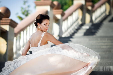 fashion photo of beautiful woman with dark hair in luxurious wedding dress posing outdoor.の写真素材