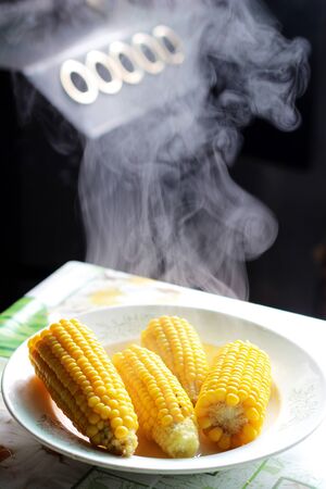 cooked hot yellow sweet corn on plate with steam on the dinner tableの写真素材