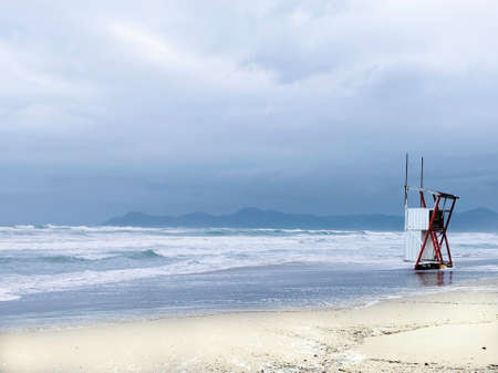 Rough sea on the beach in Mallorca. Waves run into the sand. Lone rescue tower.の写真素材