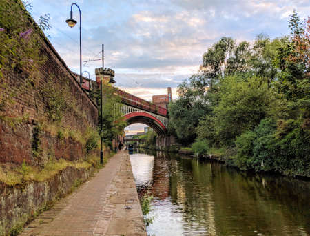City Manchester UK channel and bridge. Reflection on the water. Old and modern buildings. Blue sky. Industrial city. Red bricks.の写真素材