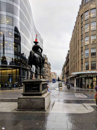 Glasgow central street view after rain, new office buildings, shops, stores. Rain water reflection. Monument with orange road rectangular on the head.のeditorial素材