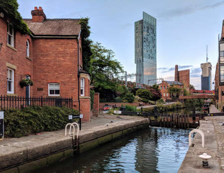 City Manchester UK channel and bridge. Reflection on the water. Old and modern buildings. Blue sky. Industrial city. Red bricks.のeditorial素材