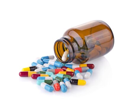 Pill bottle spilling pills on to surface isolated on a white background.の写真素材