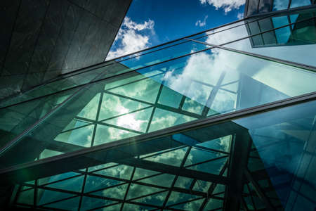 Underside panoramic and perspective view to steel blue glass high rise building with reflectionsの写真素材
