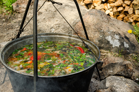 A pot of soup is hung over the fire. In the background there are firewood.の写真素材