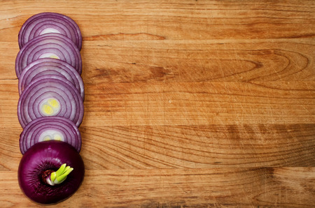Red onion in sliced circles on a wooden cutting board. Background. Free field on the right.の写真素材