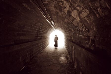 Woman goes from us to the light in the tunnelの写真素材