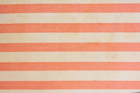 A fragment of the upholstery of an old mattress with red and white stripes. The fabric is aged, there are traces of dirt and liquid drips. Background. Texture.の写真素材