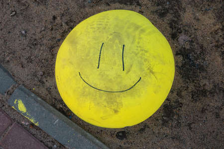 A round yellow concrete fence is on the ground. The drawn lines make the hemisphere look like a smiling emoticon. Shoe marks are visible on the surface. Background.の写真素材