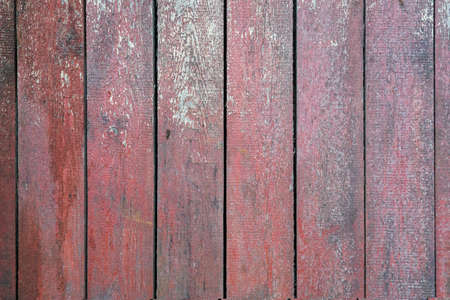 An old wooden wall made of vertically attached rough planks. There are residues of reddish-brown paint and burrs on the wood material. Background. Texture.の写真素材