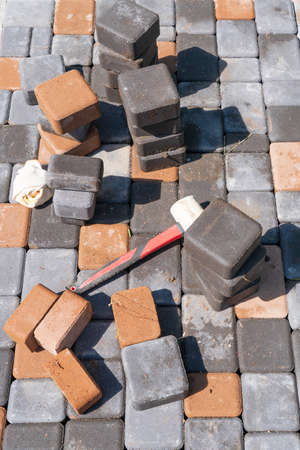 Fragment of the site, covered with paving slabs in the process. Available in black and yellow unfinished stones, as well as a working plastic hammer. Background. Texture.の写真素材