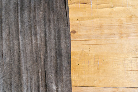 Close-up of the surface of an old plywood sheet. The left half has a gray and uneven top layer. The...