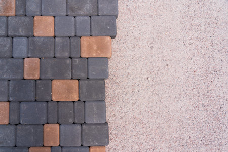 Top view of the sidewalk manufacturing stage. On the left - laid black and yellow tiles, on the...