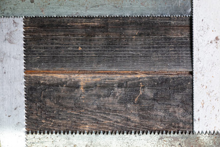 Four steel saw blades form a frame, teeth inward, against the background of an old wooden wall. The...