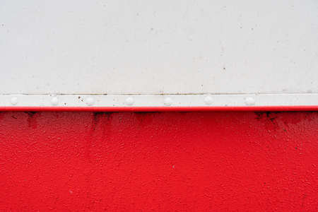 Fragment of the metal side of the boat, white and red. The waterline is located in the middle of the frame. Background. Texture.の写真素材