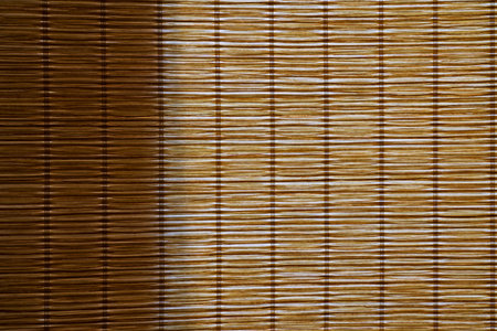 Light from the window comes through a curtain made of bamboo straw. Part of the surface is in shadow. Background. Texture.の写真素材