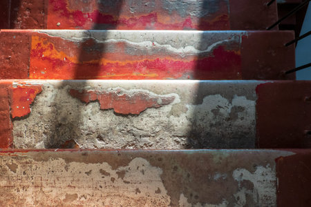 Top view of the steps of an old stone staircase going down. There are frayed residues of glue and paint layers and bright window light. Background. Texture.の写真素材