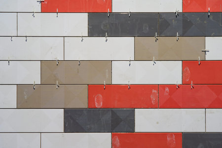 Fragment of a wall faced with multi-colored tiles of different colors at the time of construction....
