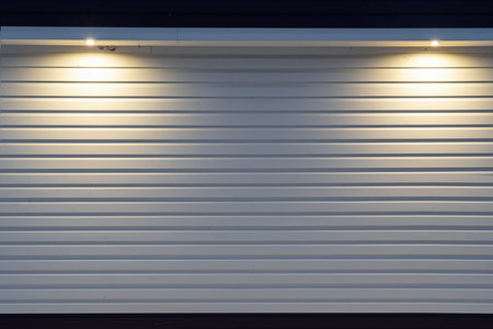The wall of the house is lined with light-colored plastic siding. There is light from two lanterns...