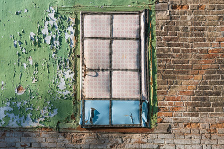 Old brick wall of a dilapidated old village house. In the middle is an aged door, upholstered with oilcloth. Background, texture.の写真素材