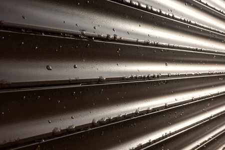 A perspective look at a brown roller shutter. There are drops of rain and sunlight on the surface....