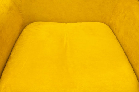 Fragment of the seat of an upholstered chair with a bright yellow surface. Background. Texture.