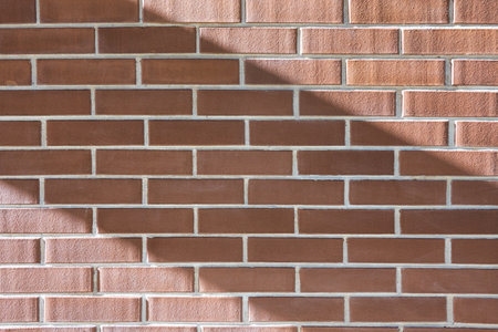 Brown brick house wall with diagonal shadow stripe. Background. Texture. Blank.の写真素材