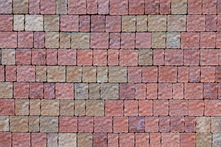 Top view of a pavement made of paving slabs of different shapes and colors. Red and gray tones....