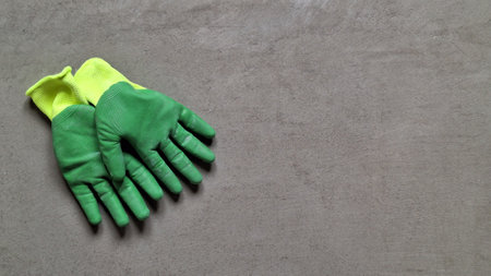 Yellow and green work gloves lie on a flat concrete surface. Background. Texture. There is space for text.の写真素材
