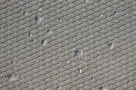Close-up of the surface of a gray concrete slab. There is a pattern of many diamonds and dents and chips. Background. Texture.の写真素材