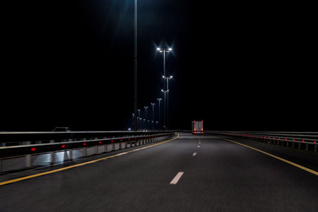 The night highway curves, street lights are on, a moving truck is visible. Background. Landscape.の写真素材
