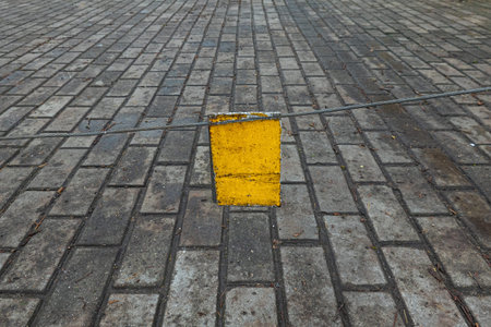 Close-up. Yellow metal sign attached to a cable that closes off the entrance area. Surface covered...