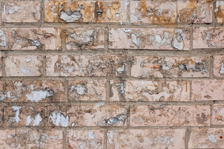 Old dirty pink brick wall. There are many remains of removed paper advertisements. Close-up....