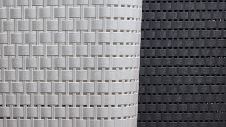 Close-up of the woven surfaces of plastic household baskets. The white one is in the foreground, the...