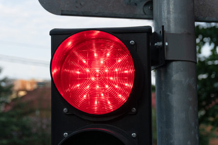 Close-up of a street traffic light. The red prohibiting light is on. There is a round glass...